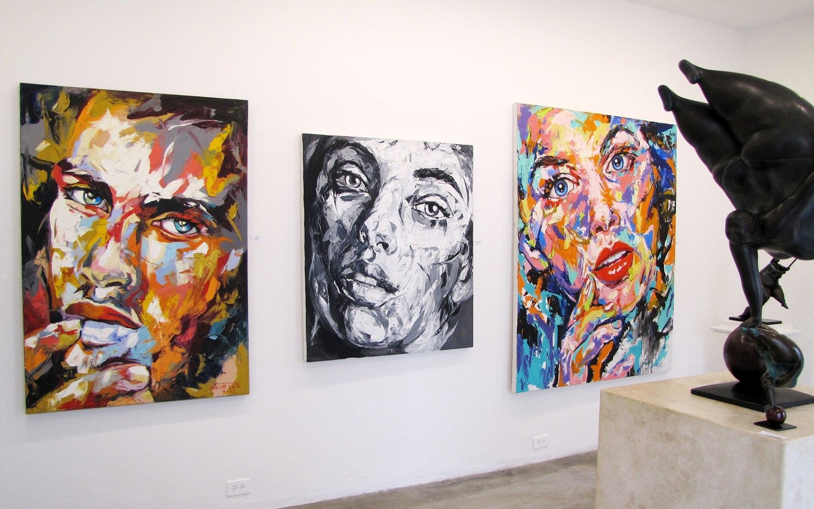 Colorful abstract portraits and modern sculptures displayed inside an art gallery in Puerto Vallarta, featuring expressive brushstrokes, vibrant hues, and contemporary artistic style.