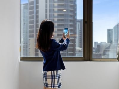Woman taking a photo with her smartphone at UniLodge Brisbane City.