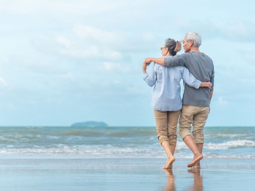 Elderly couple walking on the beach  hugging each other near Bilmar Beach Resort