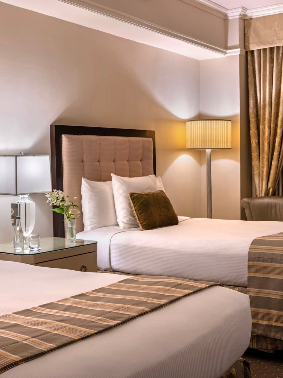 Cozy twin bedroom featuring striped bed runners with table lamps in Premier City View 2 Double Beds at Warwick New York