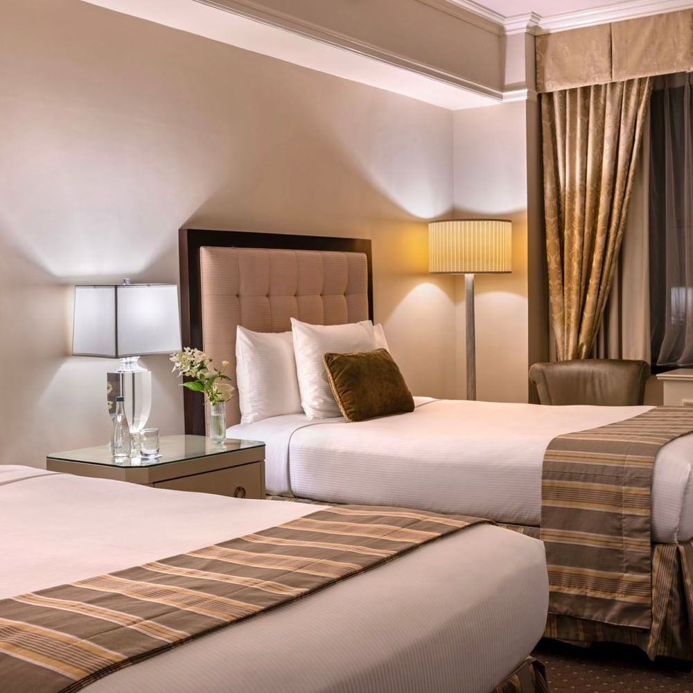 Cozy twin bedroom featuring striped bed runners with table lamps in Premier City View 2 Double Beds at Warwick New York