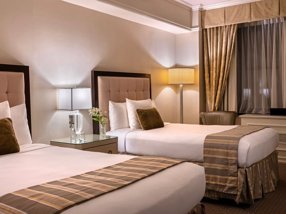 Cozy twin bedroom featuring striped bed runners with table lamps in Premier City View 2 Double Beds at Warwick New York