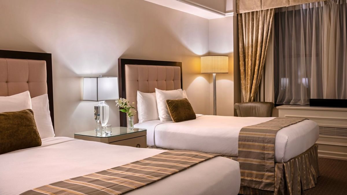 Cozy twin bedroom featuring striped bed runners with table lamps in Premier City View 2 Double Beds at Warwick New York