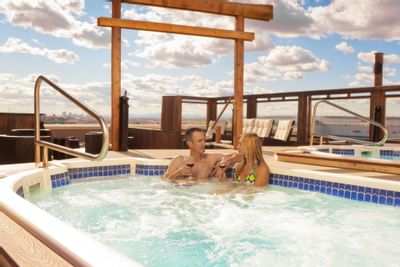 A couple enjoying a glass of wine in hot tub at Clique Hotels