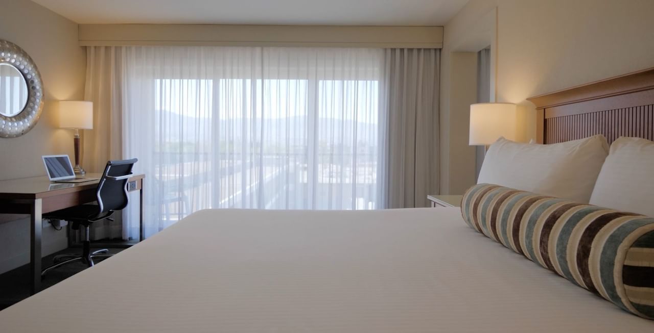 Hotel room with king bed with mirror, working table, chair, and mirror