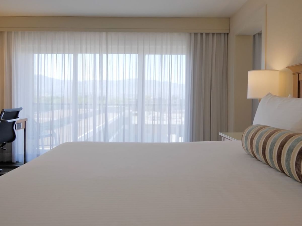 Guest room with king bed, large window, desk and chair