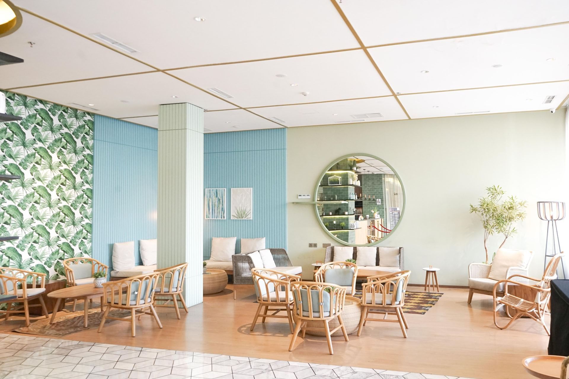 A lobby with a large round mirror and a green wall at LK Pemuda Semarang Hotel & Residences