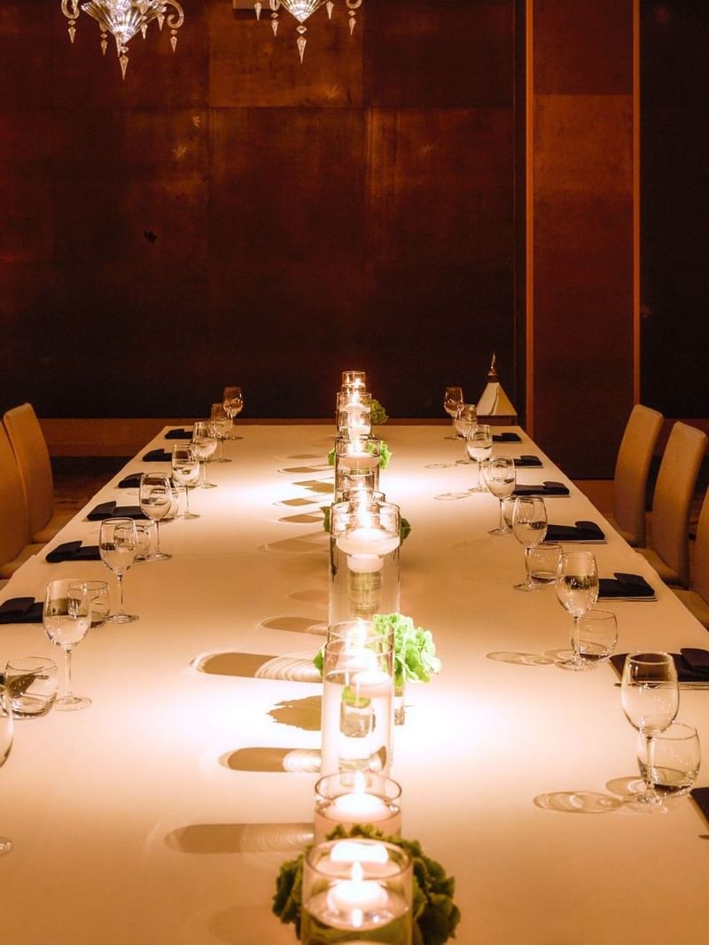 Long table set for formal dinner with candles and glassware at The May Fair Hotel, London.