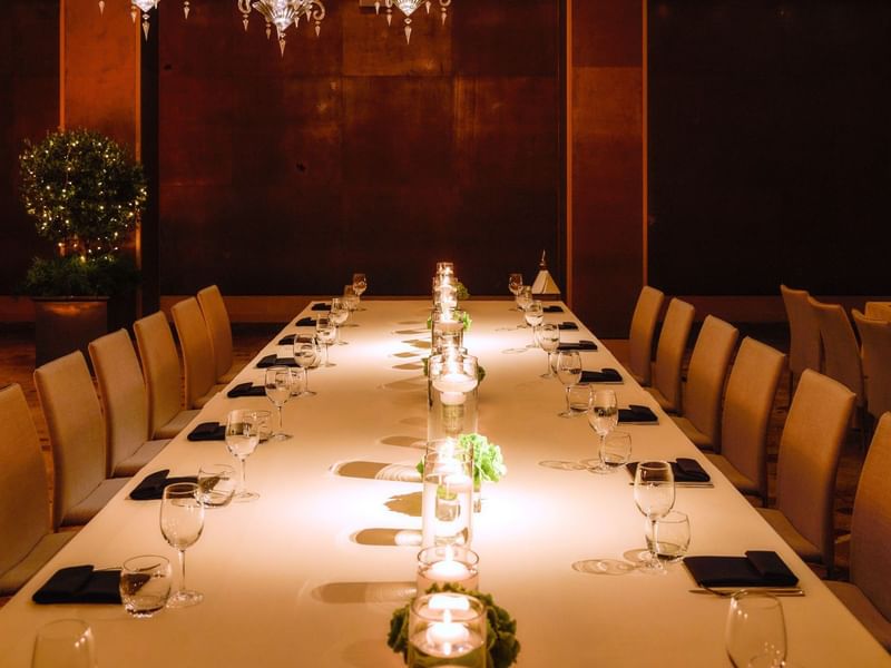 Long table set for formal dinner with candles and glassware at The May Fair Hotel, London.