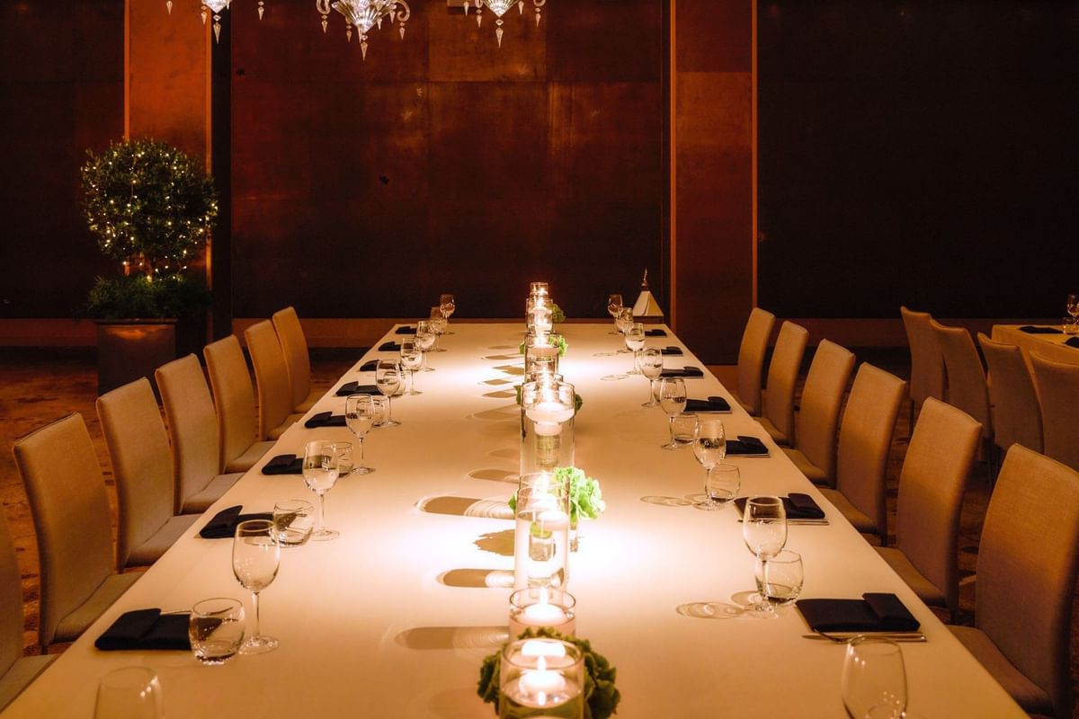 Long banquet dining table fully set with glasses and glowing candles in The Crystal Room at The May Fair Hotel
