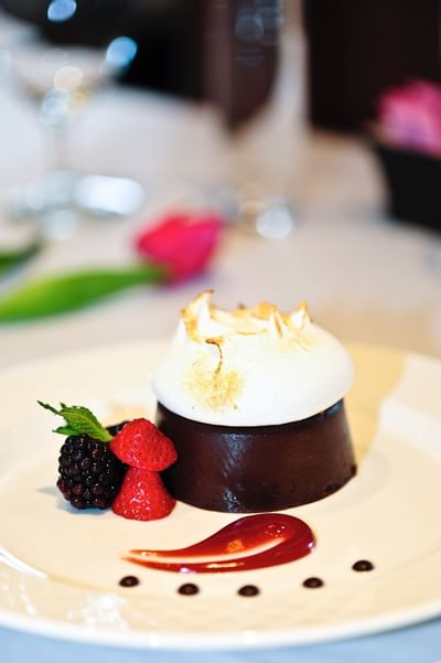 Chocolate dessert with toasted meringue topping and fresh berries arranged on a white plate, dining at The Simsbury Inn