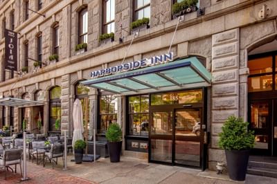 Granite historic facade with glass entrance doors and a lit overhead sign at Harborside Inn Boston