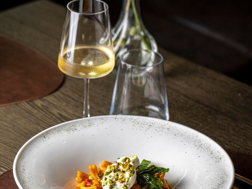 An Italian pasta dish with a glass of red wine served at EMME Restaurant