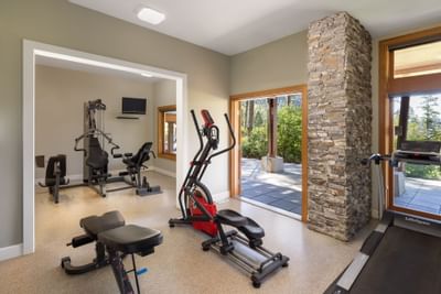 Home gym with exercise equipment, a stone column, and sliding doors leading to an outdoor patio.