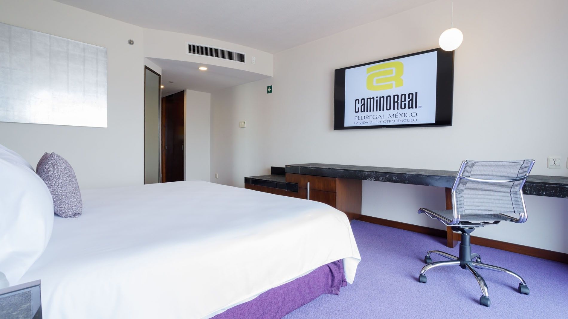 King Deluxe at Camino Real Pedregal Mexico, showing a branded TV screen, work area, and purple carpeting