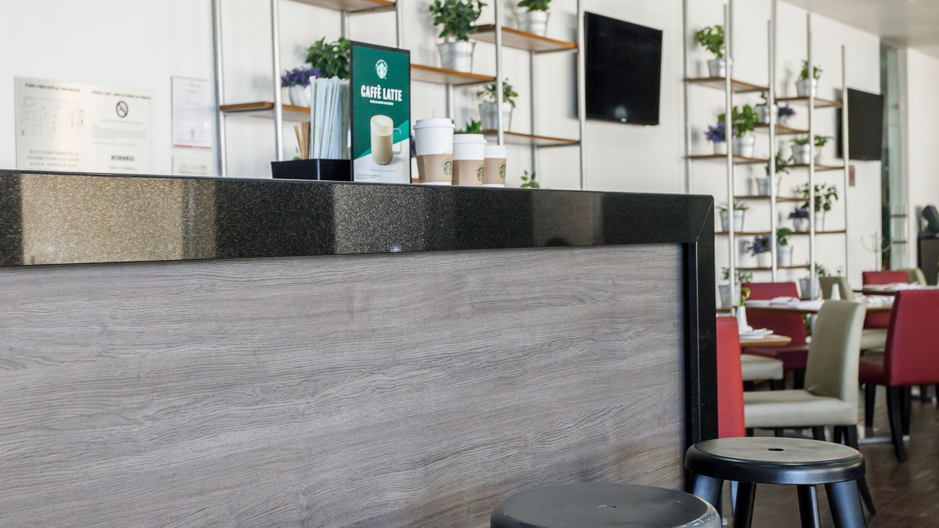 Stylish Kiosko bar showcasing a sleek counter, stools, and decorative wall shelving at Real Inn Torreon