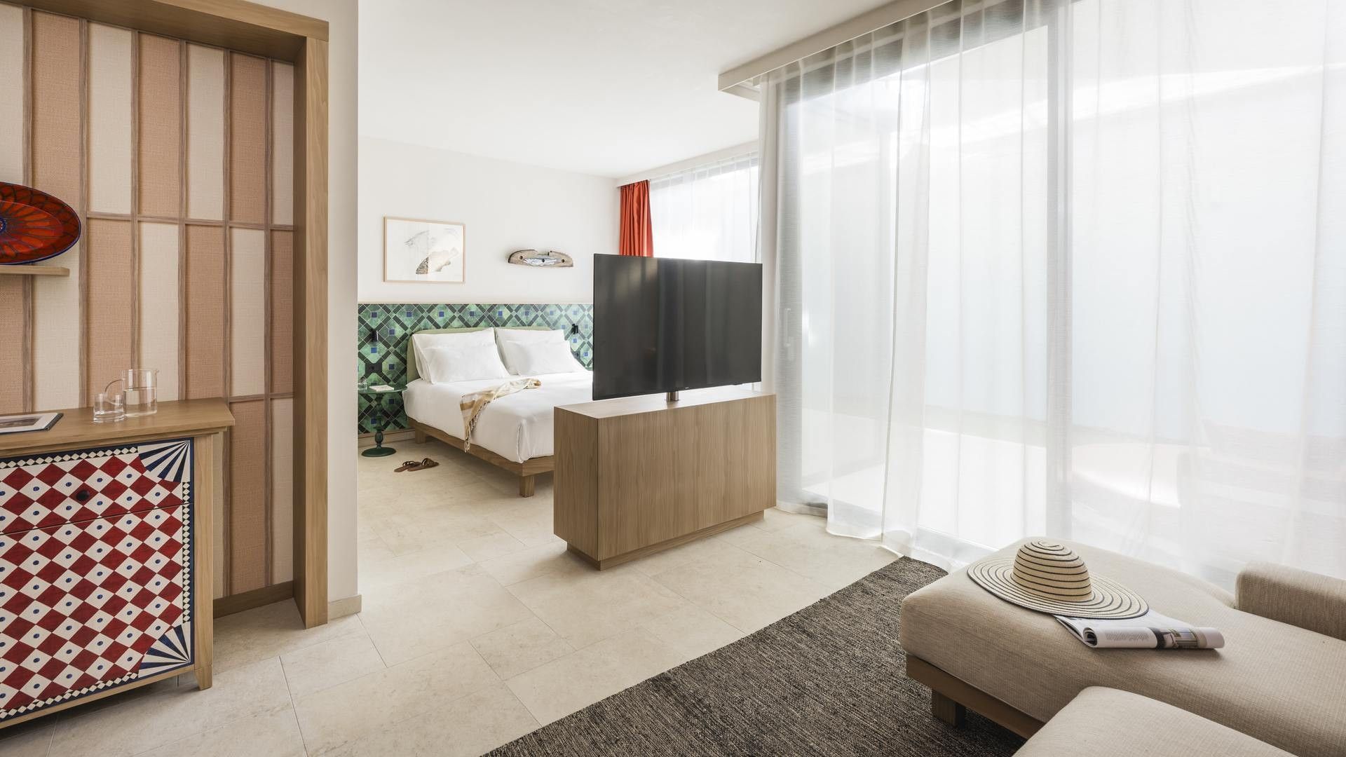 Camera d'albergo moderna con letto, TV, divano, e decorazioni eleganti.