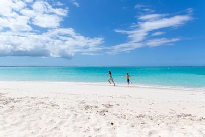 Kids running on the beach near The Somerset On Grace Bay