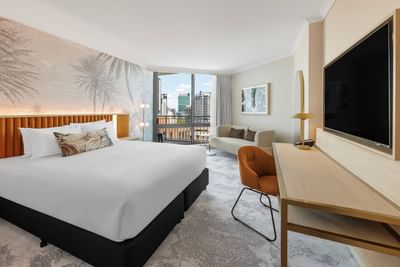 Cozy bed arranged with working desk and TV in hotel room at Amora Hotel Group