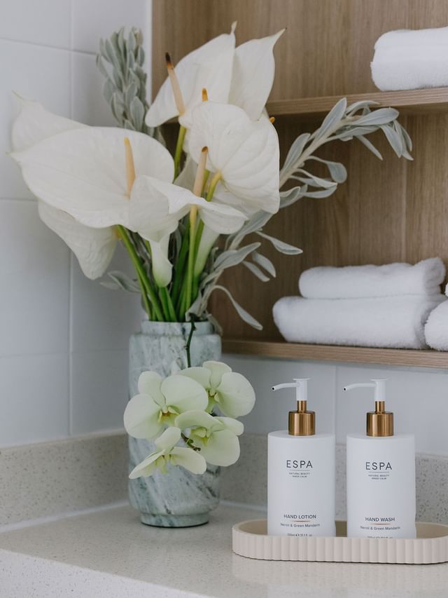 Ocean View Terrace Twin at Elysium Manly with a marble vase of flowers by ESPA bottles under folded towels on a shelf nearby