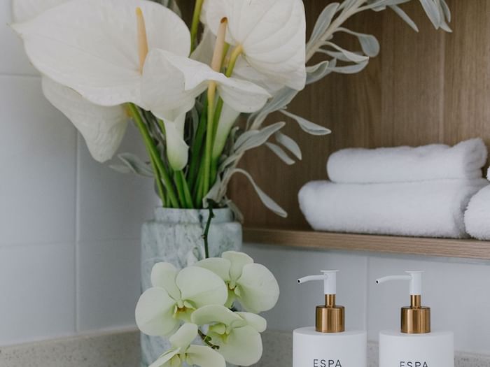 Ocean View Terrace Twin at Elysium Manly with a marble vase of flowers by ESPA bottles under folded towels on a shelf nearby
