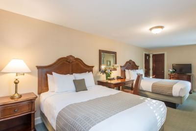 TV, nightstand, and work desk by the beds in a cozy room at The Exeter Inn
