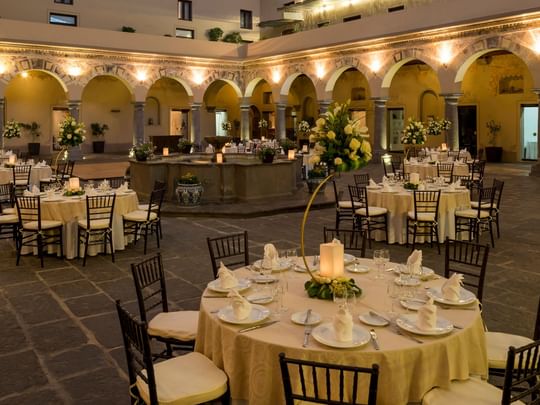 Elegantly set tables with flowers and lit candles in Patio Novicias at Quinta Real Puebla, Heroica Puebla de Zaragoza.