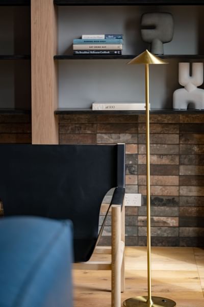Floor lamp & lounge chair by a shelf at Nesuto Docklands