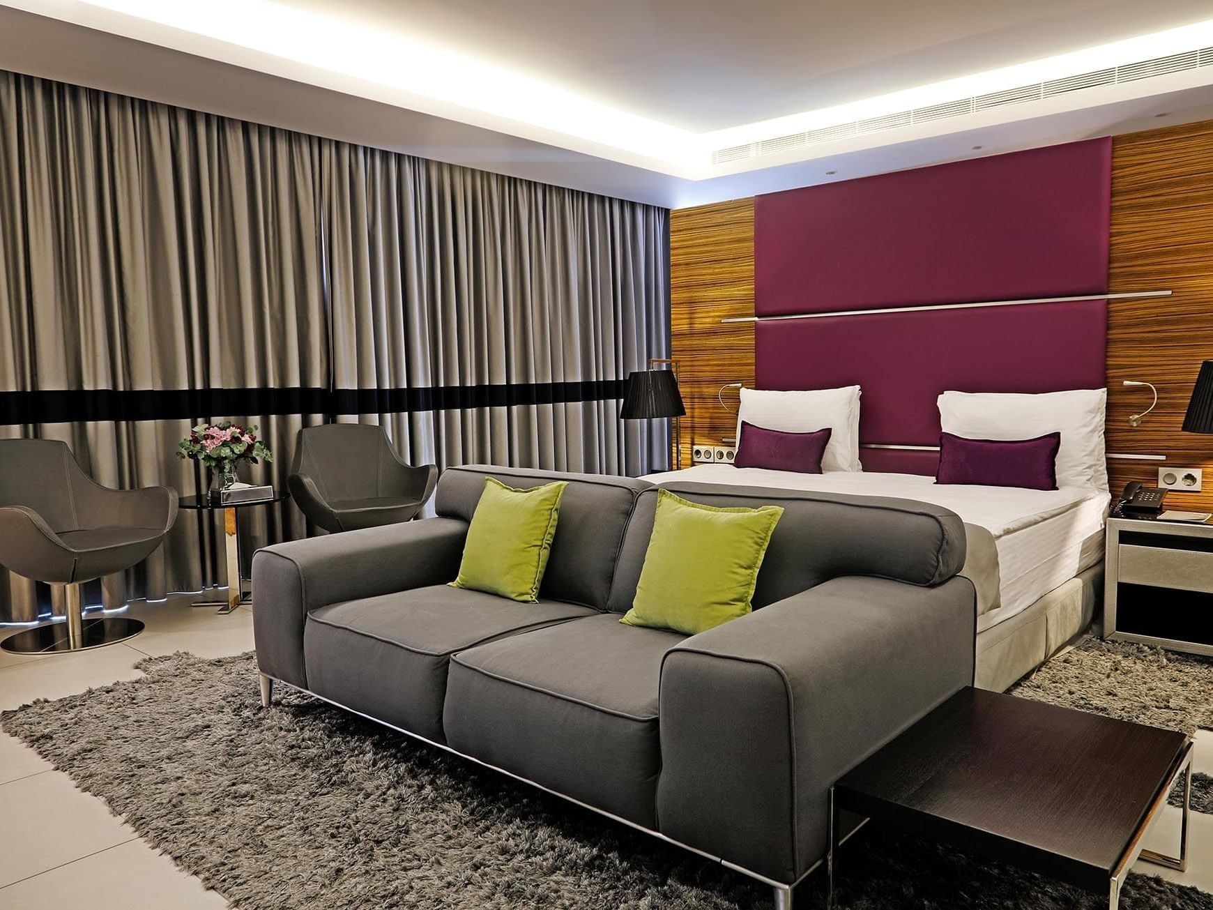 Junior Suite features Grey sofa by swiveling chairs under a purple headboard at Warwick Stone 55 - Beirut