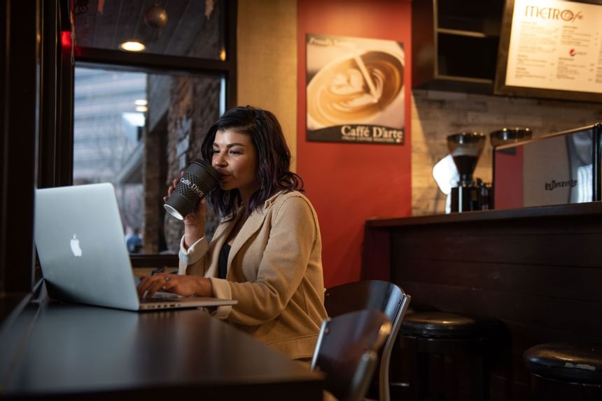 A girl drinks coffee while working at  Hotel 43