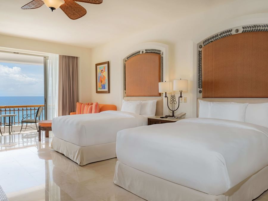Two comfortable Double beds with a balcony and a couch in Junior Suite Ocean View at Marquis Los Cabos Resort