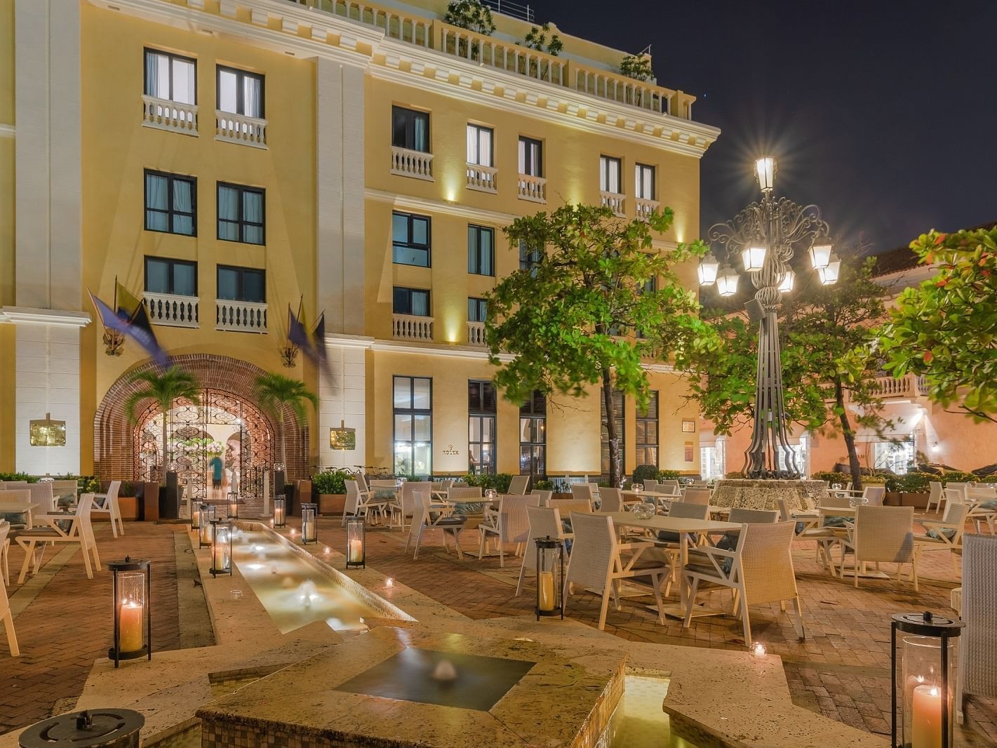 Plaza Santa Teresa restaurant at Hotel Charleston Santa Teresa, Cartagena de Indias, with outdoor seating, candles, and a fountain.