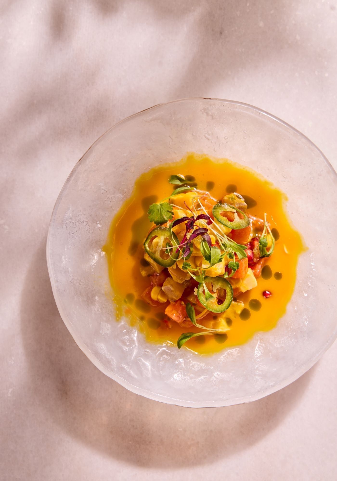 Un ceviche gastronomique aux couleurs éclatantes, servi dans un bol en verre transparent chez Whitcomb's, au sein de l'hôtel The Londoner