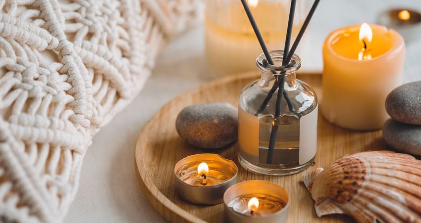 A calming arrangement of candles, essential oil bottle, pebbles, & seashell on a tray at Sunset Plaza Beach Resort