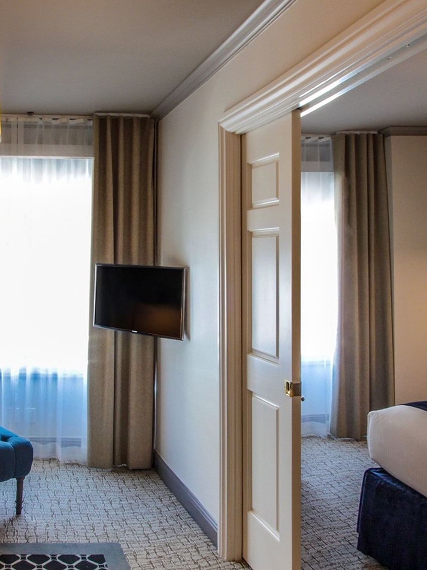 Suite features Teal armchair under a drum lamp by a wall-mounted TV at Warwick San Francisco
