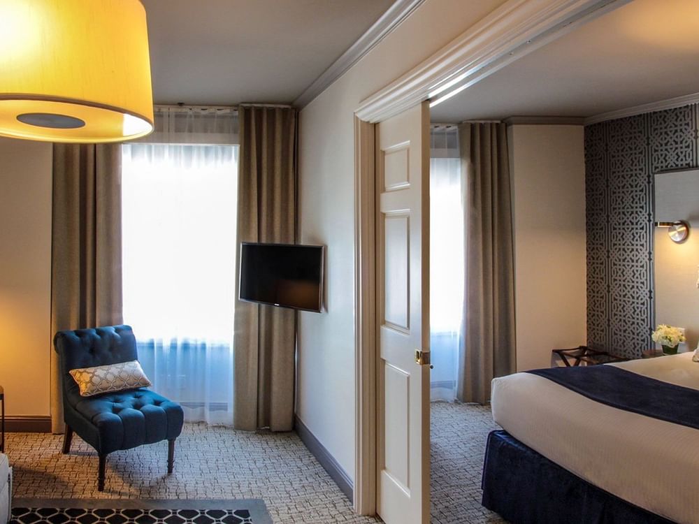 Suite features Teal armchair under a drum lamp by a wall-mounted TV at Warwick San Francisco