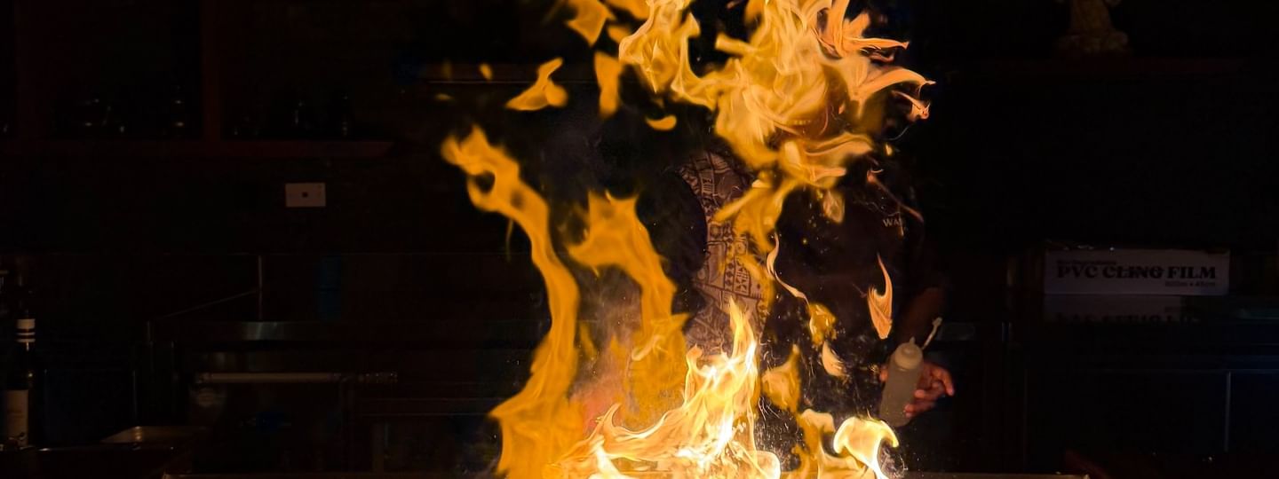 Flames rise above a hibachi grill with wine glasses at Sazanami, Warwick Fiji Resort and Spa in Korolevu