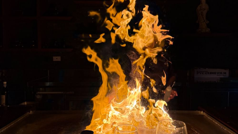 Flames rise above a hibachi grill with wine glasses at Sazanami, Warwick Fiji Resort and Spa in Korolevu.