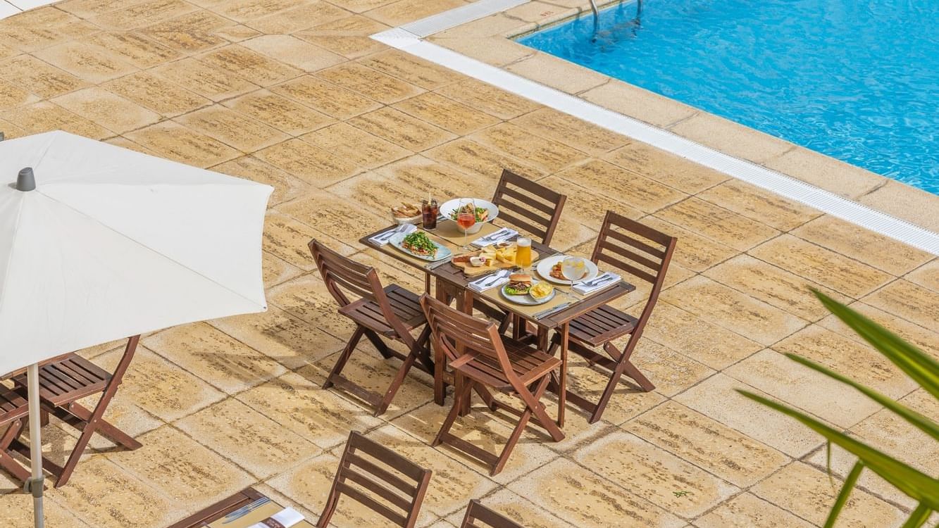 Meals served on a table by the outdoor pool in Bar Atlântida at São Miguel Park Hotel