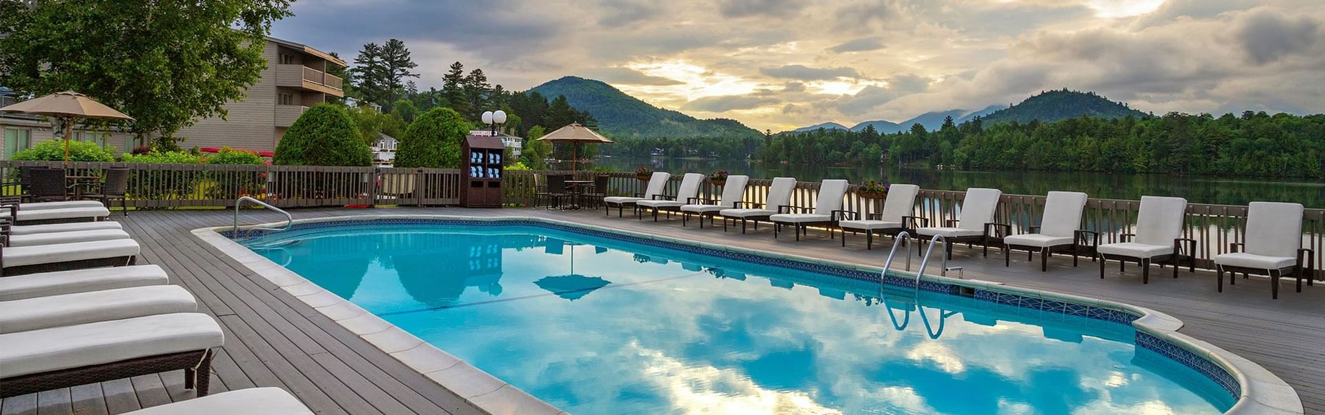 Swimming pool and lounge chairs on a deck with a scenic view of a lake and mountains at High Peaks Resort
