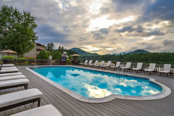 Swimming pool and lounge chairs on a deck with a scenic view of a lake and mountains at High Peaks Resort