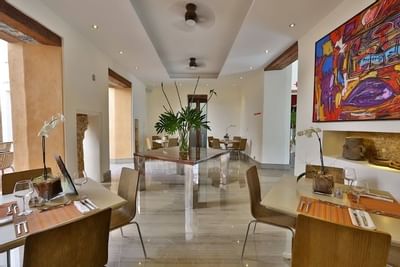 Castil Restaurant interior with sleek furniture, vibrant artwork, and elegant table settings at Billini Hotel Historic Luxury