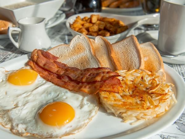 Plate with eggs, bacon, toast, and hash browns.