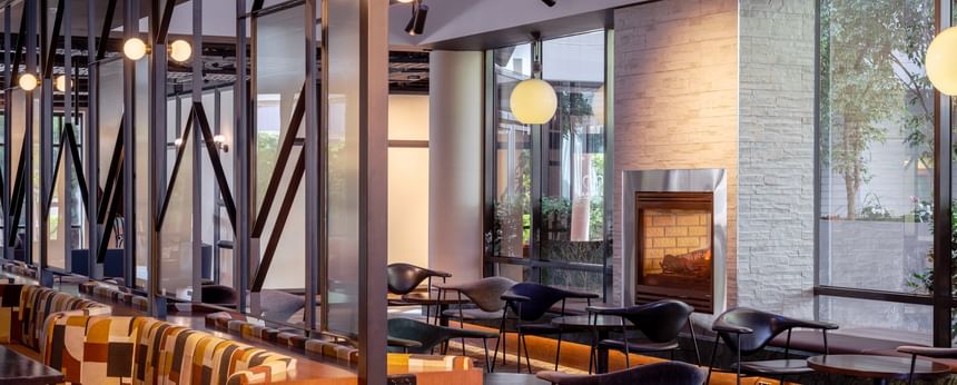 Modern lounge with geometric decor, featuring a fireplace and elegant black chairs at Amora Herencia Riverwalk Melbourne