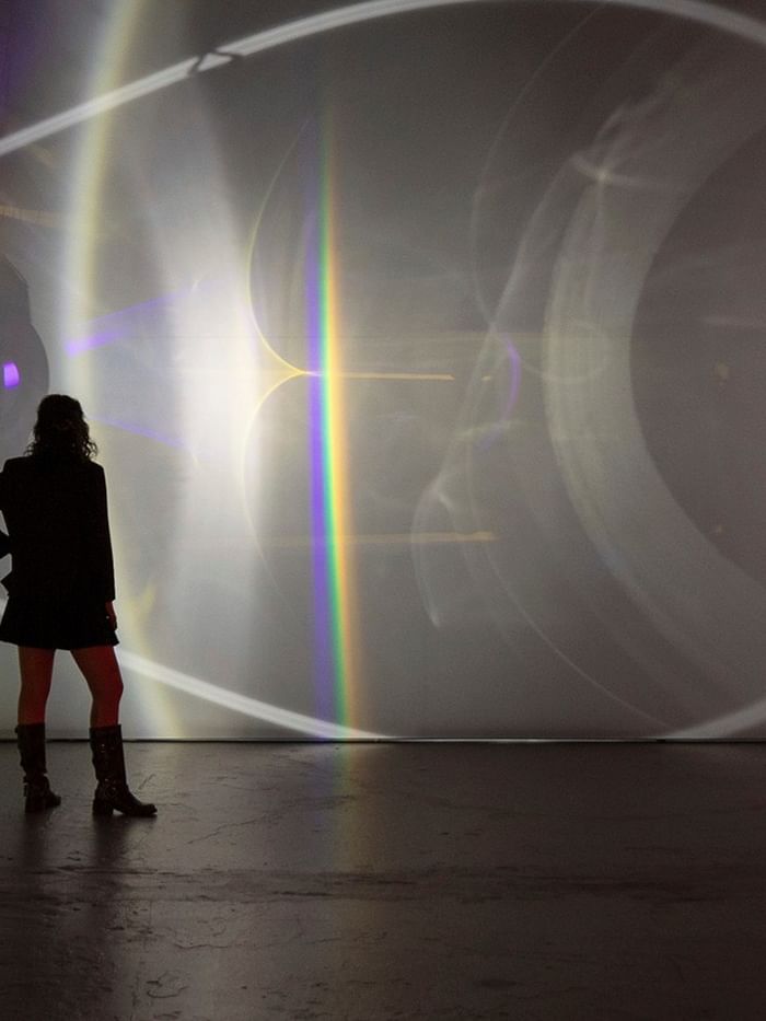 Woman standing in front of Olafur Eliasson's Presence light installation.