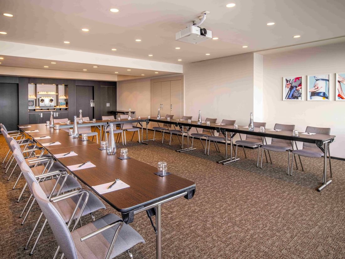 Meet 26 three meeting room setup with U-shaped table arrangement, chairs, and water bottles at The Hotel Brussels