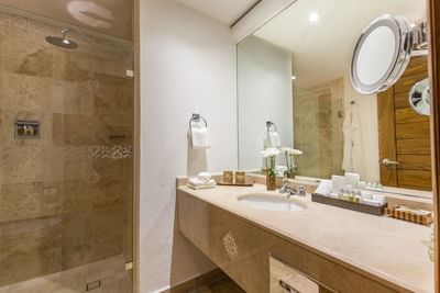 An elegant hotel bathroom featuring a double marble vanity, modern lighting, and a large mirror.