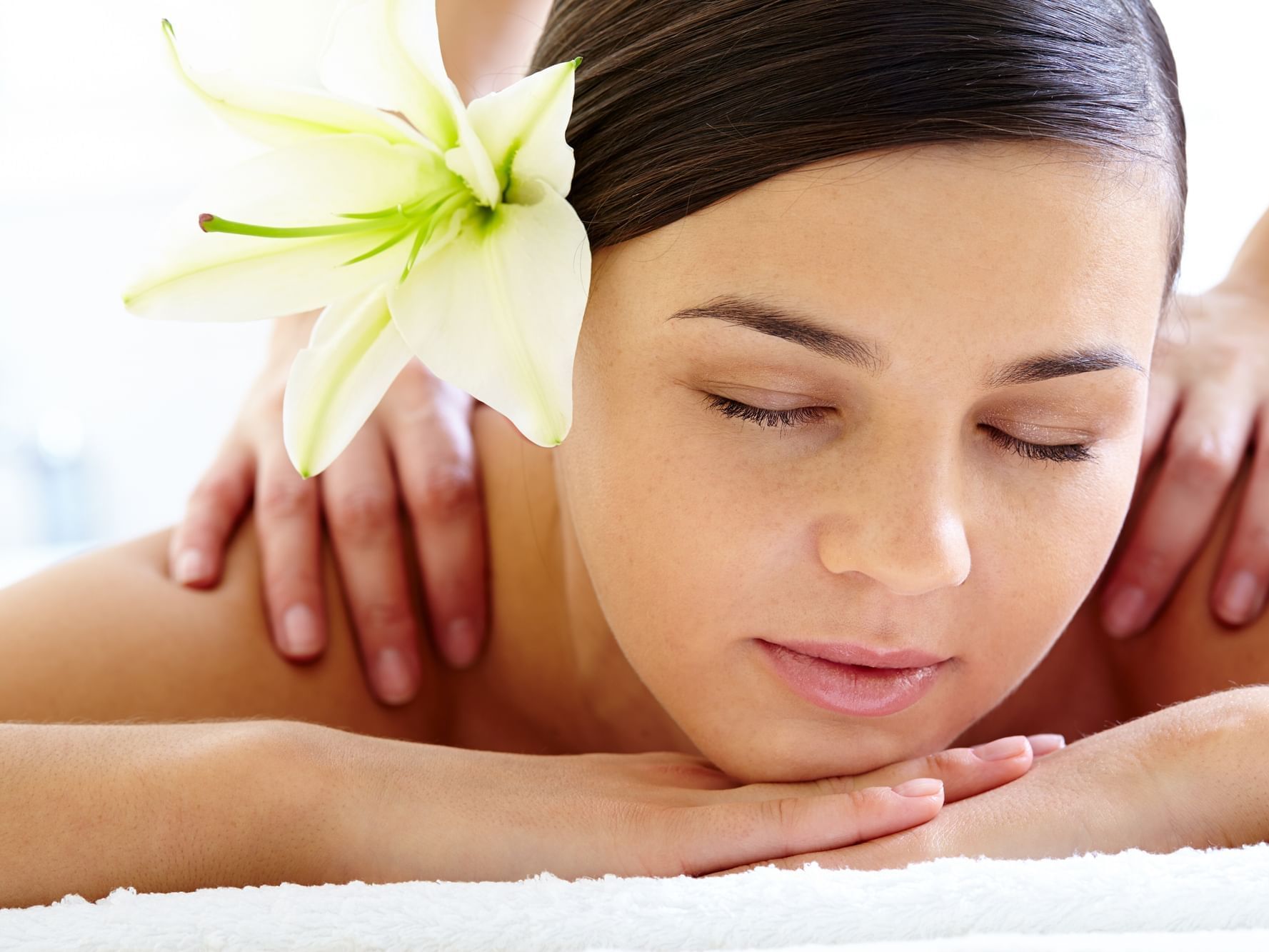 Woman with flower on the ear having a massage