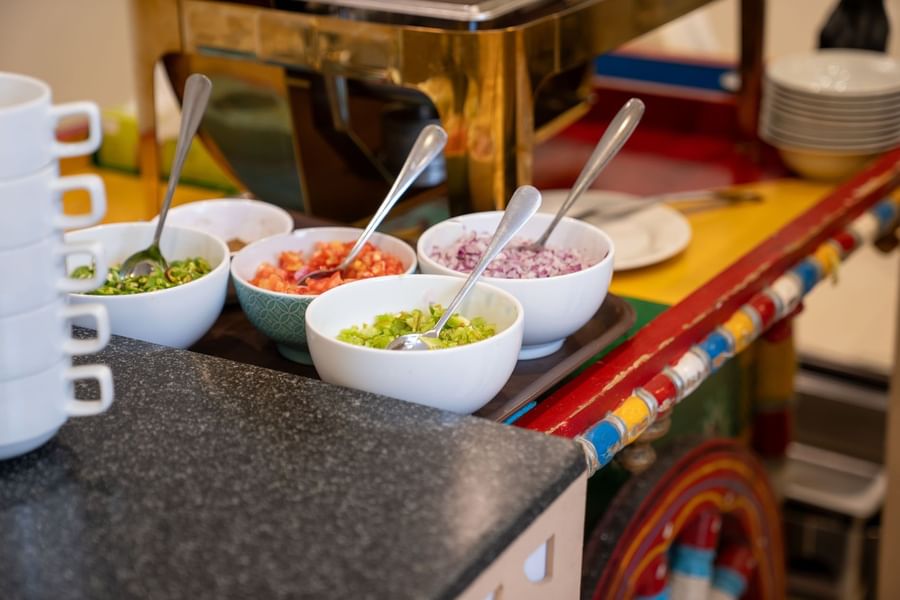 Assorted fresh toppings, including chopped tomatoes and onions, in bowls at Saja by Warwick Makkah