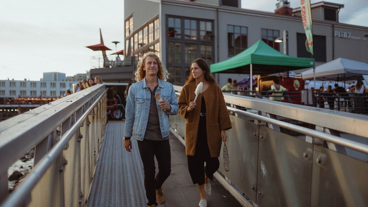 A couple walking by the waterfront with ice creams.